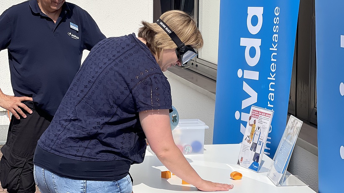 Menschen testen eine Aktion am Messestand der vivida bkk.